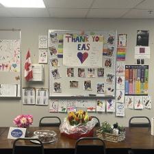 Thank you messages and pictures set up on a staff room bulletin board for Support Staff Appreciation